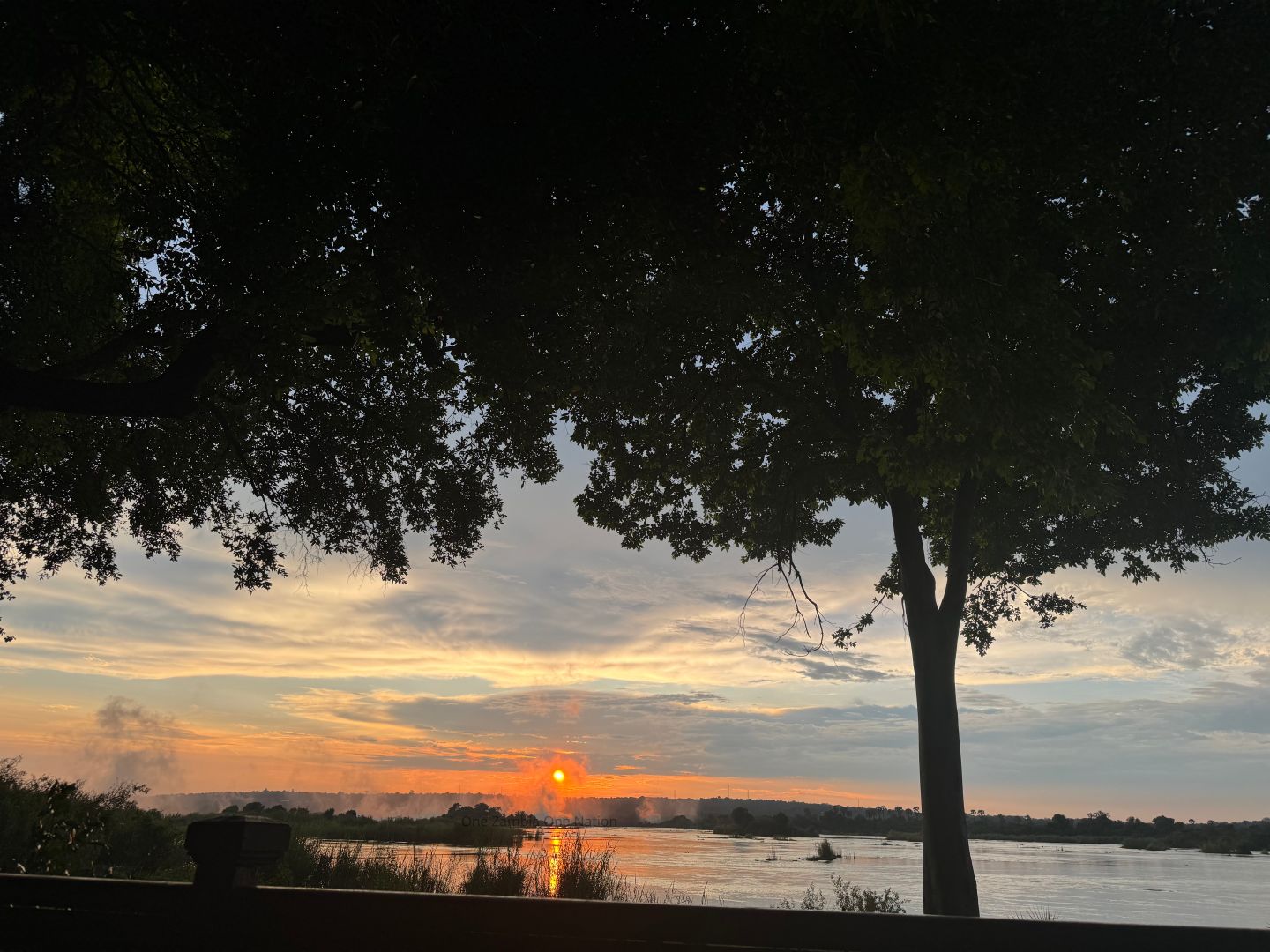 Sunset over the Zambezi River with Victoria Falls mist in the distance